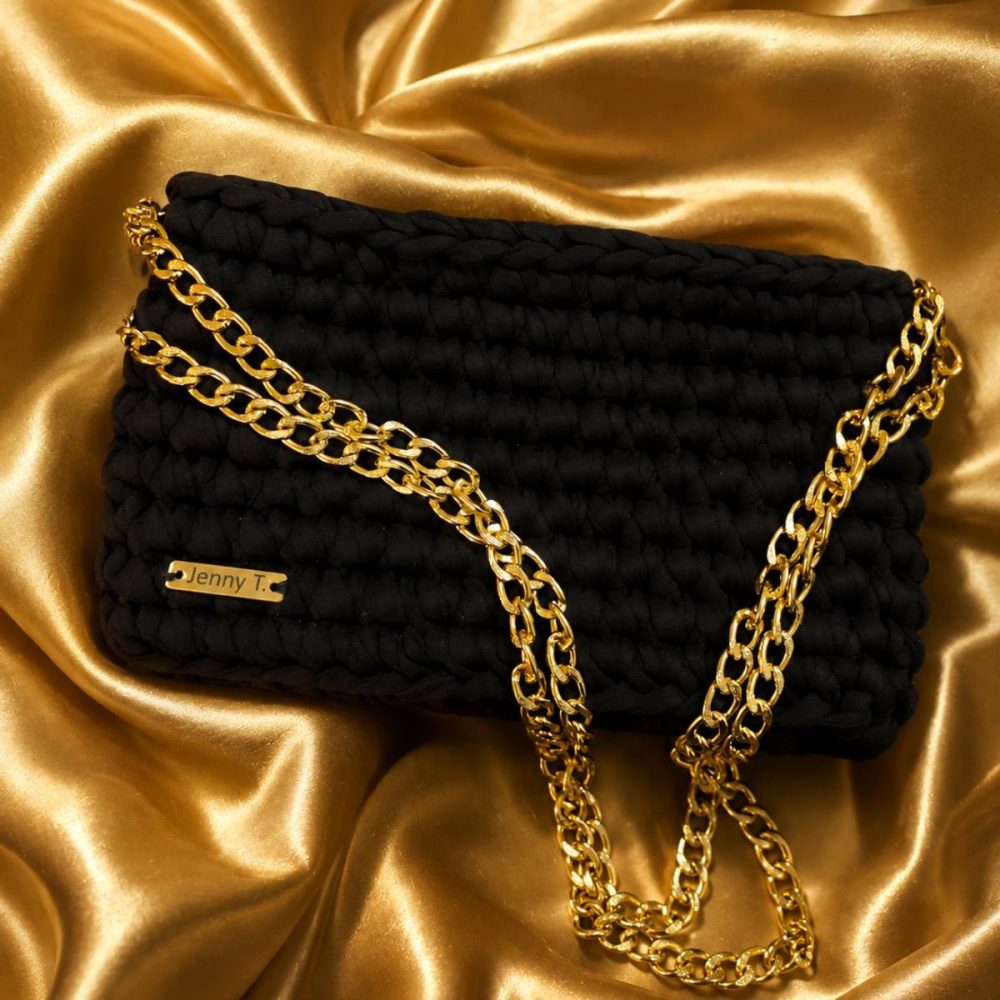 Μαύρο πλεκτό clutch με χρυσαφί αλυσίδα πάνω σε χρυσό σατέν